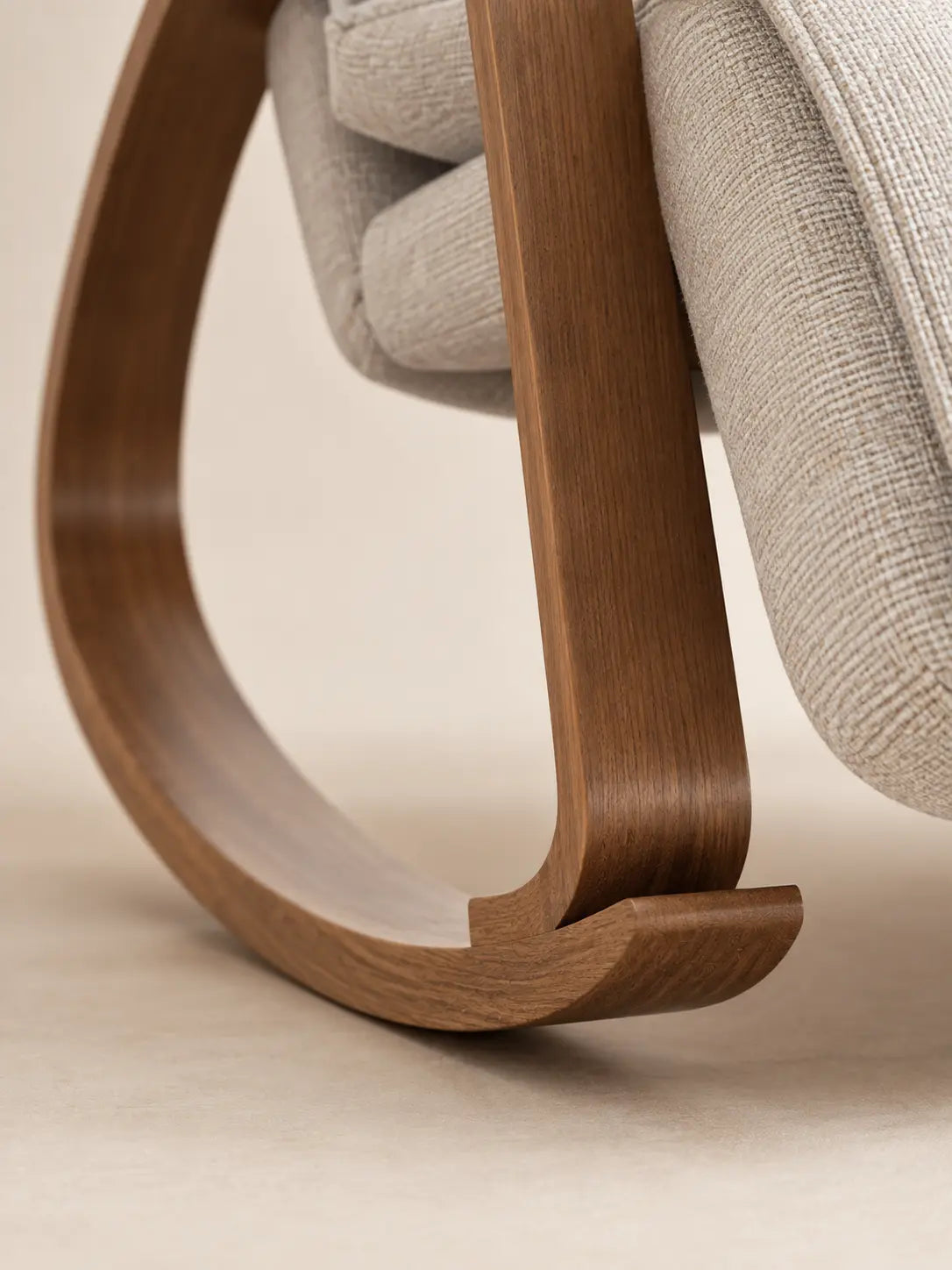Gros plan sur la structure en bois courbé et le piètement à bascule du fauteuil Youki